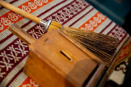 A beautiful Traditional Broom and a Wooden Box carefully placed on vibrant Textile fabricの写真素材