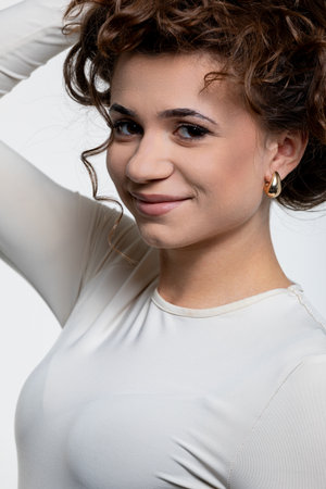 A portrait of a young woman with curly hair, in stylish attire, showcasing her individualityの写真素材