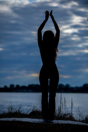 A silhouetted figure at dusk by a serene water body, harmonizing with natureの写真素材