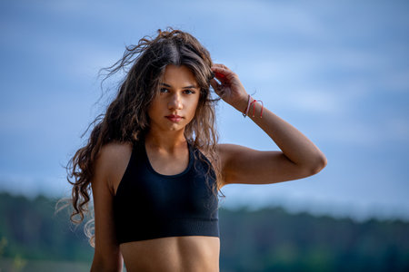 A Young Woman in a Sporty Pose by the Beautiful Water, Radiating Confidence and Energyの写真素材