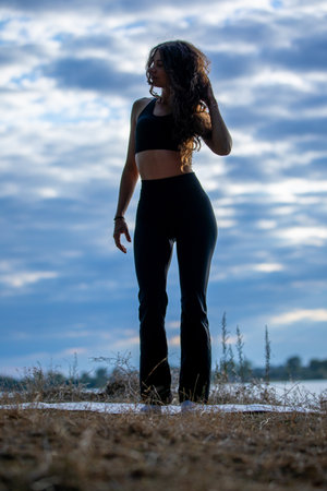 The Silhouette of a Woman Standing Gracefully Against a Dramatic and Colorful Skyの写真素材