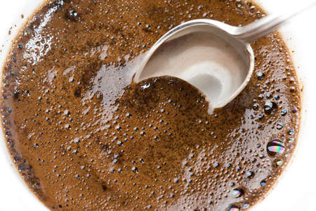 Teaspoon in a thick foam of ground coffee の写真素材