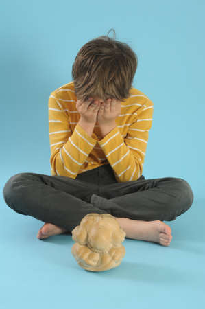 Boy in maditation with a statue of Buddhaの写真素材