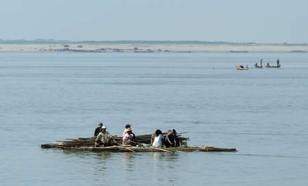 River Ayeyarwady, Myanmar - 20 January 2010: People on a raft with timber cruising on the river Ayeyarwady, Myanmarのeditorial素材
