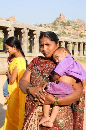 Hampi, India - 12 January 2015: woman with her child in her arms in front of Vittala temple at Hampi on Indiaの写真素材