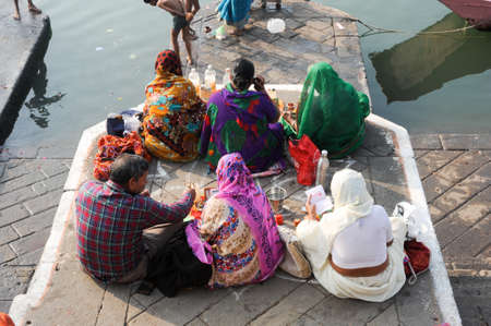 Maheshwar, India - 3 February 2015: People performs morning pooja on sacred river Narmada ghats in Maheshwar, India. To Hindus Narmada is one of 5 holy rivers of Indiaのeditorial素材