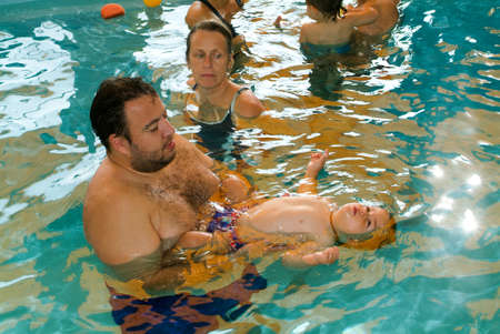 Lugano, Switzerland - 18 October 2007: Adorable babys enjoying swimming in a pool with with their relatives, early development class for infants teaching children to swim and diveのeditorial素材