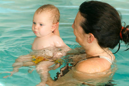 Lugano, Switzerland - 18 October 2007: Adorable baby enjoying swimming in a pool with his mother, early development class for infants teaching children to swim and diveのeditorial素材