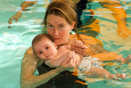Lugano, Switzerland - 18 October 2007: Adorable baby enjoying swimming in a pool with his mother, early development class for infants teaching children to swim and diveのeditorial素材