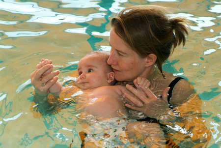 Lugano, Switzerland - 18 October 2007: Adorable baby enjoying swimming in a pool with his mother, early development class for infants teaching children to swim and diveのeditorial素材