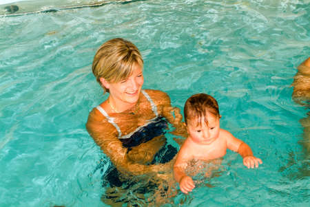 Lugano, Switzerland - 18 October 2007: Adorable baby enjoying swimming in a pool with his mother, early development class for infants teaching children to swim and diveのeditorial素材