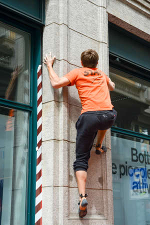 Lugano, Switzerland - 9 May 2015: Man climbing a house wall on street boulder contest at Lugano on Switzerlandのeditorial素材