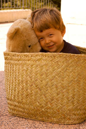 Two years old boy with his plush bear on a basketの写真素材
