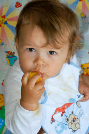 Nine month old baby male eating a peachの写真素材