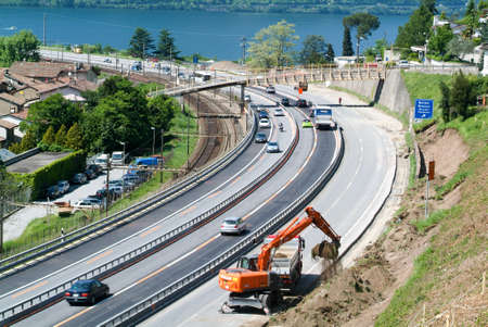 Bissone Switzerland  28 May 2008: Workers breaking up a wall with a Hydraulic digger on a highway at Bissone on Switzerlandのeditorial素材