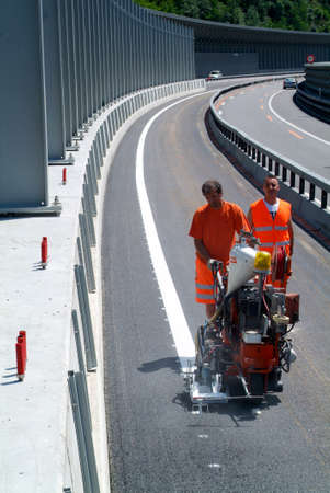 Bissone Switzerland  20 June 2011: Machine eject and worker on road and traffic sign paintingのeditorial素材