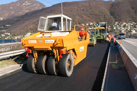 Bissone Switzerland  2 March 2007: Workers and vehicles during the asphalting of the highway at...