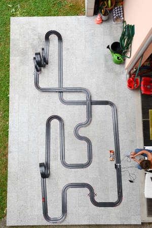 Lugano, Switzerland - 26 July 2015: Boy playing with a Car Racing Track on the gardenのeditorial素材