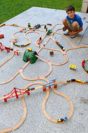 Lugano, Switzerland - 29 August 2015: boy playing with a wooden train set on a gardenのeditorial素材