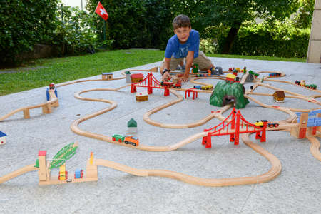 Lugano, Switzerland - 29 August 2015: boy playing with a wooden train set on a gardenのeditorial素材