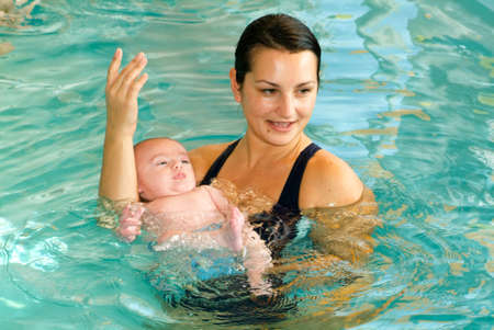 Ponte Tresa, Switzerland - 18 october 2007: Adorable baby enjoying swimming in a pool with his mother, early development class for infants teaching children to swim and diのeditorial素材
