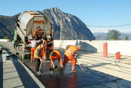 Melide, Switzerland - 12 november 2009: Workers and vehicles during the asphalting of the highway at...