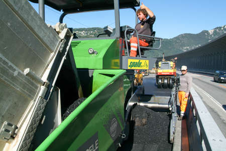 Melide, Switzerland - 29 september 2010: Workers and vehicles during the asphalting of the highway...