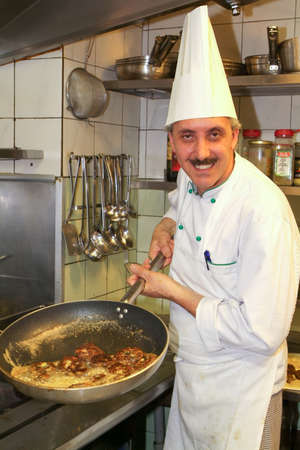 Lugano, Switzerland - 12 May 2006: cook at the stove preparing food on the kitchen of a restaurantのeditorial素材