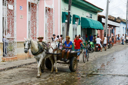 Trinidad, Cuba - 9 january 2016: people conducting on a horse cariage in front of colorful traditional houses in the colonial town of Trinidad in Cubaのeditorial素材