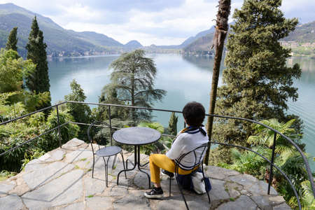 Morcote, Switzerland - 13 april 2016: woman sitting and enjoying the view from Scherrer Park to lake Lugano at Morcote on Switzerland.のeditorial素材