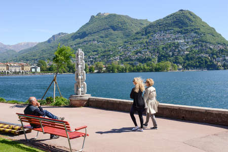 Lugano, Switzerland - 5 may 2016:  People sitting and walking on the lakeside of Lugano on the italian part of Switzerlandのeditorial素材