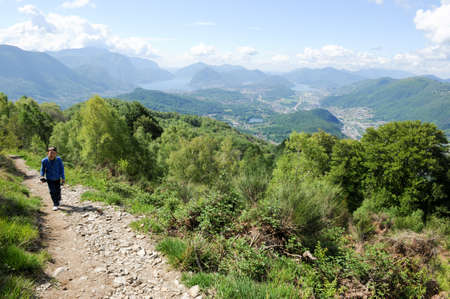 Gola di Lago, Switzerland - 16 may 2016: boy hiking on a pathway in the mountains over Lugano on the...