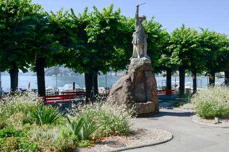 Lugano, Switzerland - 9 july 2016: Nicely decorated flower bed and trimmed bushes in front of Wilhelm Tell statue at Lugano on the italian part of Switzerland.の写真素材
