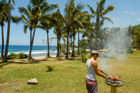 Grand Anse Beach (La reunion), France - 29 December 2002: man roasting a chicken on his grill in the beach of Grand Anse in La Reunion island, Franceのeditorial素材