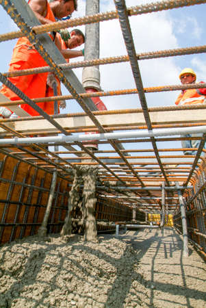 Bissone, Switzerland - 5 March 2011: Street workers pouring cement with a pump into a highway construction at Bissone on Switzerlandのeditorial素材