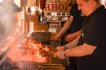 Lugano, Switzerland - April 29, 2017: Cook preparing grilled meat skewers at street food festival of...