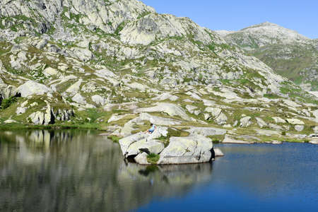 Gotthard pass, Switzerland - 5 August 2017: Boy climbing a rock at Gotthard pass on the Swiss alpsのeditorial素材