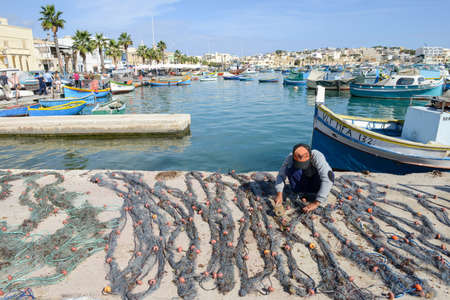 Marsaxlokk, Malta - 3 November 2017: fishermen preparing the fishing nets near their boat at...