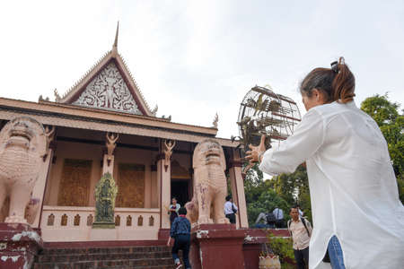 Phnom Penh, Cambodia - 17 January 2018: woman that frees birds from a cage at buddhist temple of Wat Phnom in Phnom Penh on Cambodiaのeditorial素材