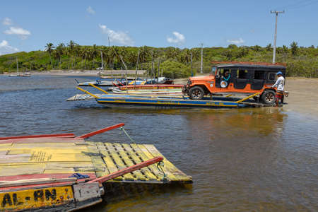 Pipa, Brazil- 23 January 2019: man trasporting a car on a raft in the river near Pipa on Brazilのeditorial素材