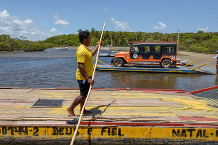 Pipa, Brazil- 23 January 2019: man trasporting a car on a raft in the river near Pipa on Brazil
