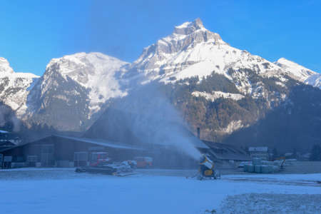Snow-machine bursting artificial snow over a skiing slope at Engelberg on the Swiss alps