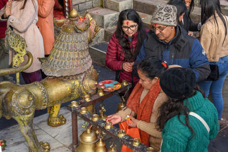 Pokhara, Nepal - 11 January 2020: people touching the prayer bells of a temple in Pokhara on Nepal