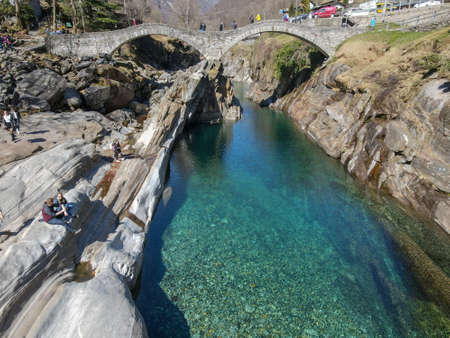 Lavertezzo, Switzerland - 24 March 2021: Tourists visiting the famous roman bridge of Lavertezzo on Verzasca valley on the italian part of Switzerlandのeditorial素材