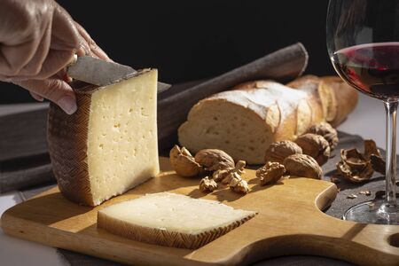 Manchego cheese and nuts on wooden table.の写真素材