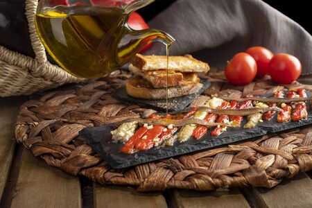 Escalivada washed down with virgin olive oil and vegetables in wicker basket on the rustic wooden tableの写真素材