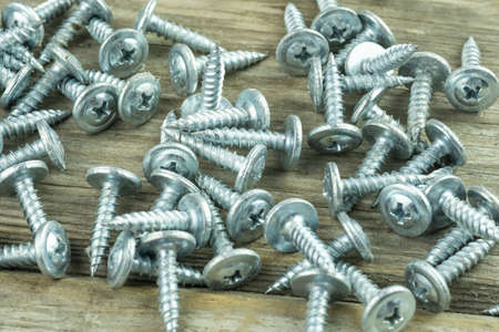Close-up of scattered large long new screws. A poster for a building materials store or catalog....