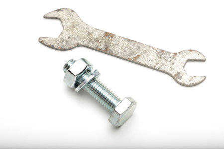 A metal wrench and a bolt with a nut are placed on a white background. The wrench is slightly rusted, while the bolt is shiny and new.の写真素材