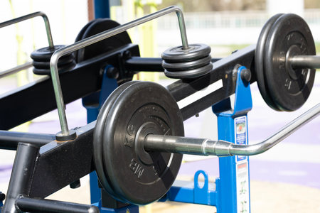 A close-up of a weightlifting barbell with black weights on a gym equipment. The setting is bright and modern, suitable for fitness enthusiasts.の写真素材