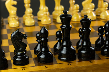 A close-up of a chessboard with black and yellow pieces arranged for a game.